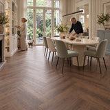 Altessa Visgraat Brown Plak PVC – sfeerbeeld: eetkamer met ronde tafel en groene stoelen, tuindeuren