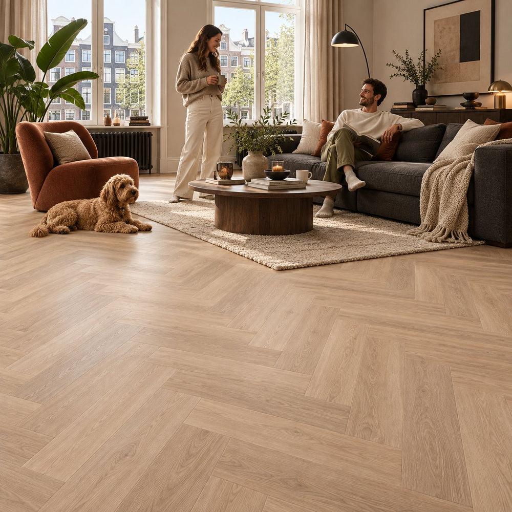 Altessa Visgraat Natural Plak PVC – sfeerbeeld: woonkamer met grijze bank, stel en hond
