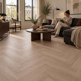 Altessa Visgraat Smoky Plak PVC – sfeerbeeld: woonkamer met donkere bank, vrouw leest
