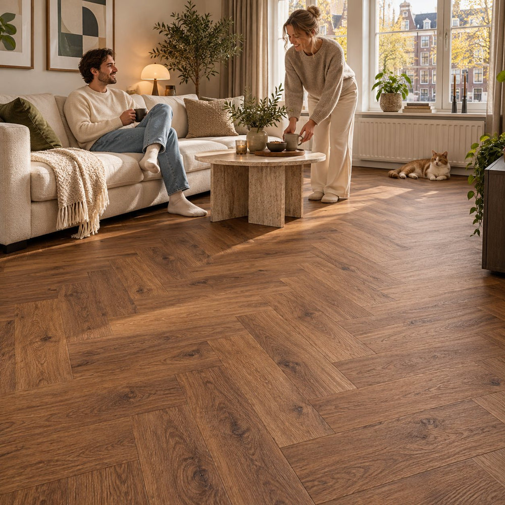 Dunea Visgraat Dark Oak Klik PVC – sfeerbeeld: woonkamer met witte bank, stel en kat