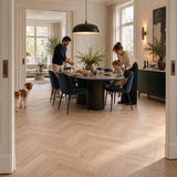 Natura Visgraat Light Oak Klik PVC – sfeerbeeld: klassieke eetkamer met donkere ronde tafel, hond in de deuropening