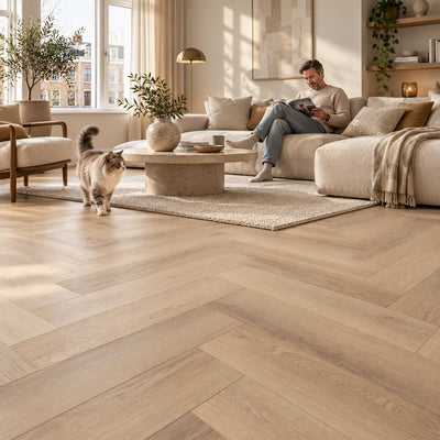 Altessa Visgraat Beige Plak PVC – sfeerbeeld: lichte woonkamer met witte bank, man leest, kat