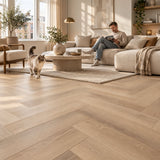 Altessa Visgraat Beige Plak PVC – sfeerbeeld: lichte woonkamer met witte bank, man leest, kat