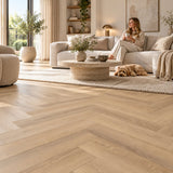 Altessa Visgraat Beige Plak PVC – sfeerbeeld: lichte woonkamer met witte bank, vrouw en hond