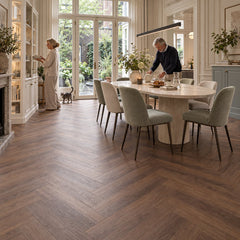 Altessa Visgraat Brown Plak PVC – sfeerbeeld: eetkamer met ronde tafel en groene stoelen, tuindeuren