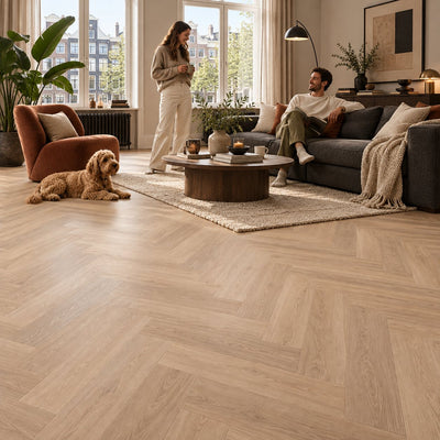 Altessa Visgraat Natural Plak PVC – sfeerbeeld: woonkamer met grijze bank, stel en hond
