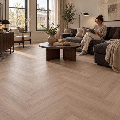 Altessa Visgraat Smoky Plak PVC – sfeerbeeld: woonkamer met donkere bank, vrouw leest