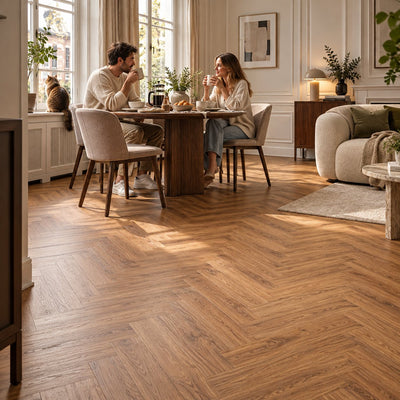 Dunea Visgraat Warm Oak Klik PVC – sfeerbeeld: eethoek met tafel, stel drinkt koffie