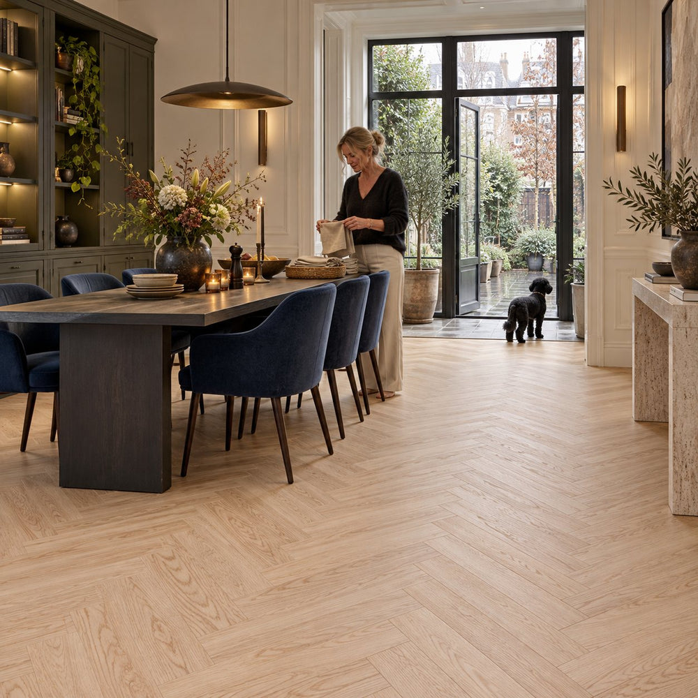 Natura Visgraat Beige Oak Klik PVC – sfeerbeeld: statige eetkamer met lange donkere tafel, open tuindeuren en hond
